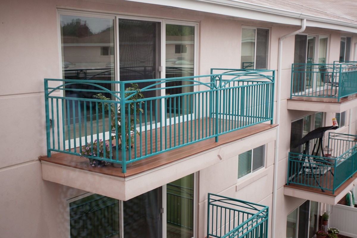 A view of a balcony with turquoise railings on an apartment building.