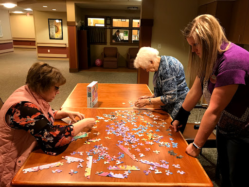 Three individuals engage in assembling a colorful puzzle together.