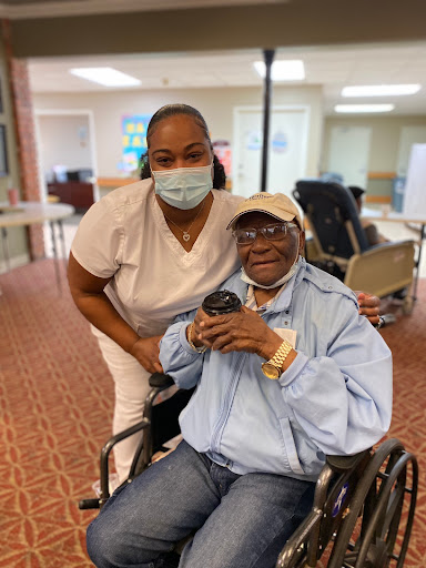 A smiling nurse poses with an elderly resident in a care facility, showcasing the compassionate environment of elder care.