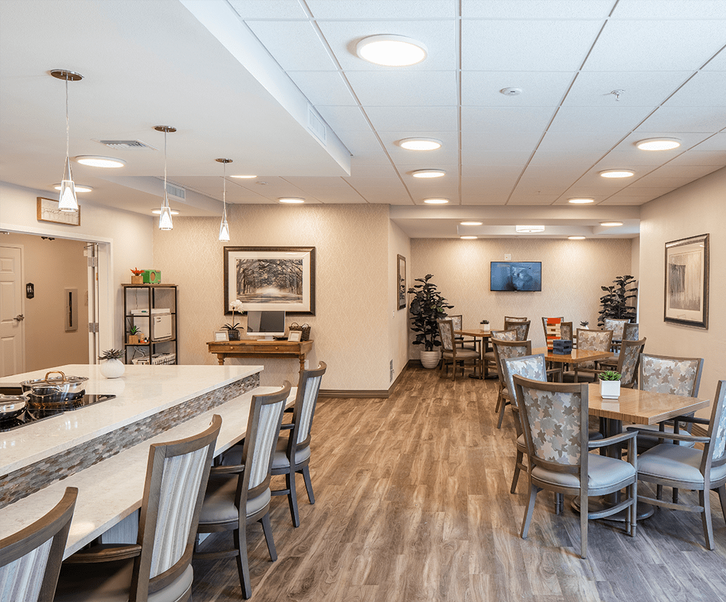 A spacious dining area with wooden flooring, decorated with tables and chairs.