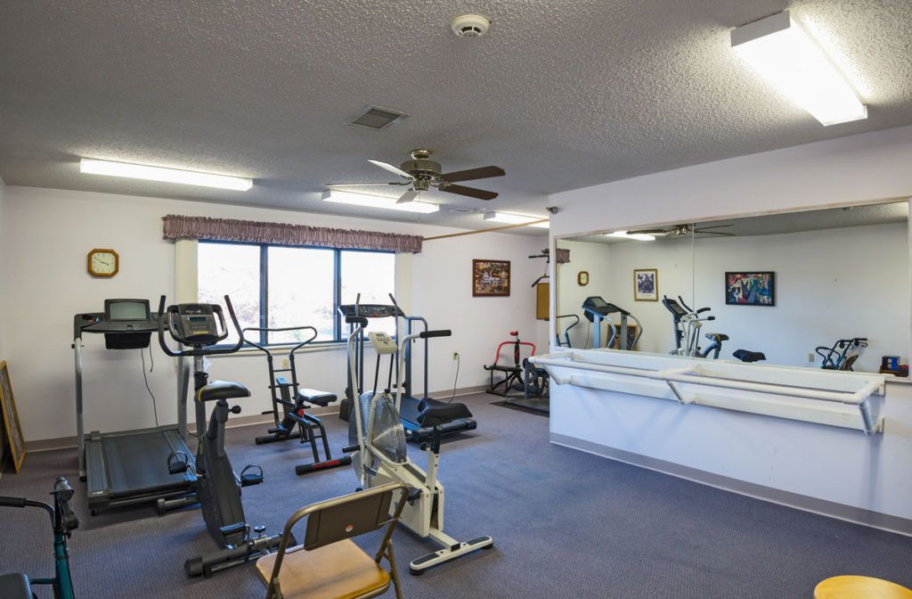 A small indoor gym with various exercise equipment and a large mirror.