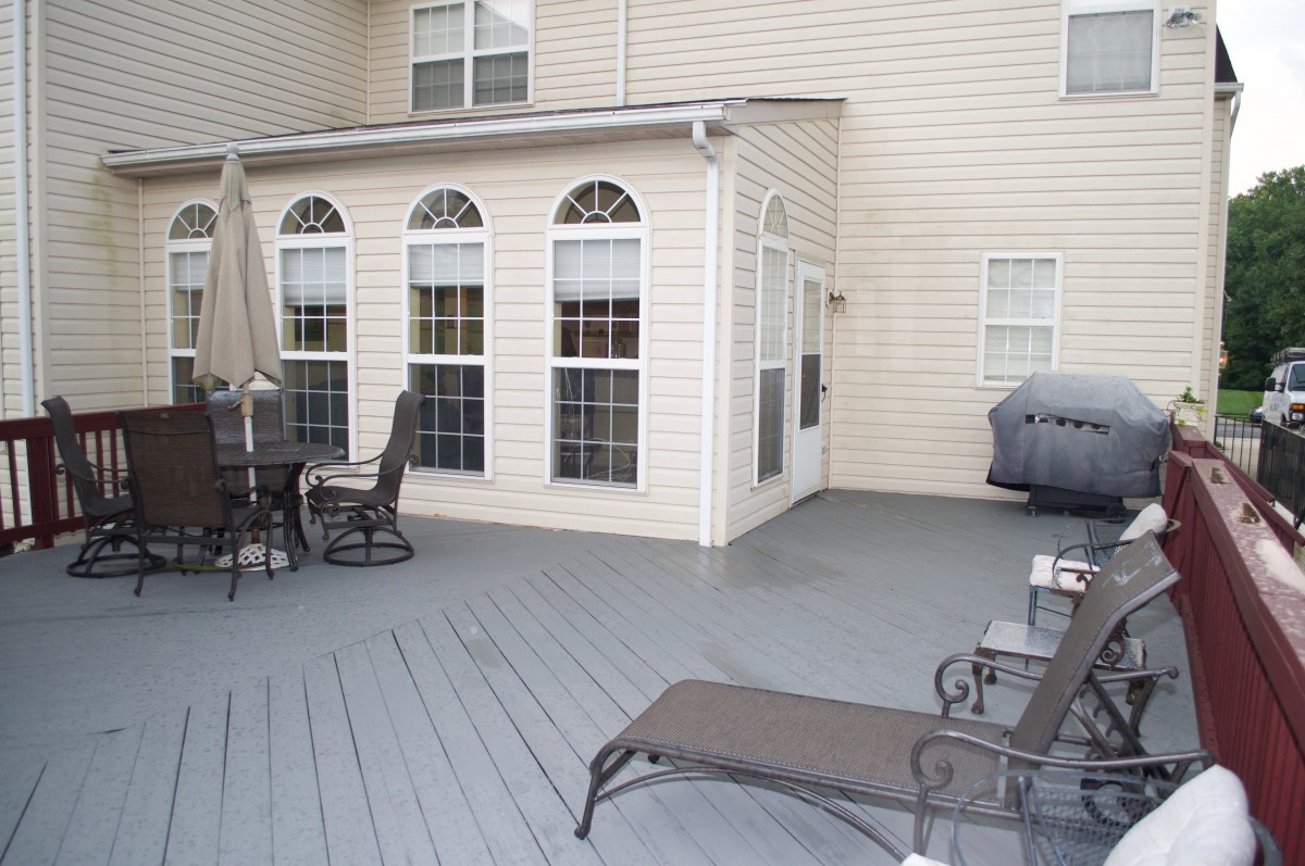 A spacious outdoor deck with patio furniture and a grill alongside the house.