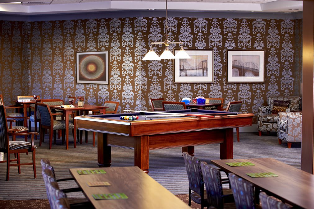 A stylish restaurant interior featuring a pool table and seating area, with decorative wall art and ambient lighting.