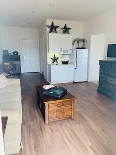 A cozy living space featuring a sofa, coffee table, and kitchenette with decorative stars.