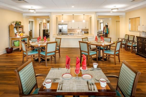 A neatly arranged dining area with tables set for guests, featuring elegant place settings and warm lighting.