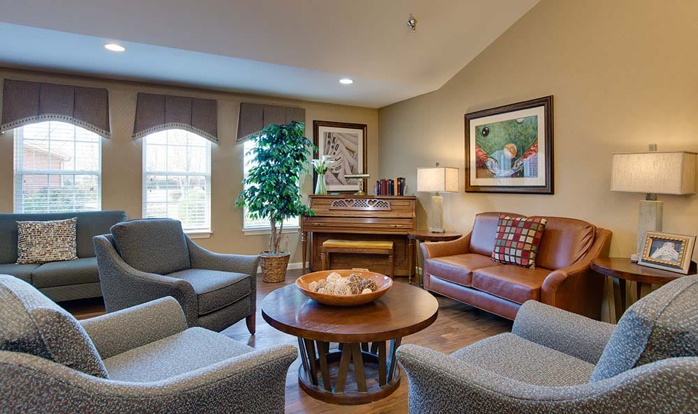 A cozy living room with a sofa, armchairs, and a piano.