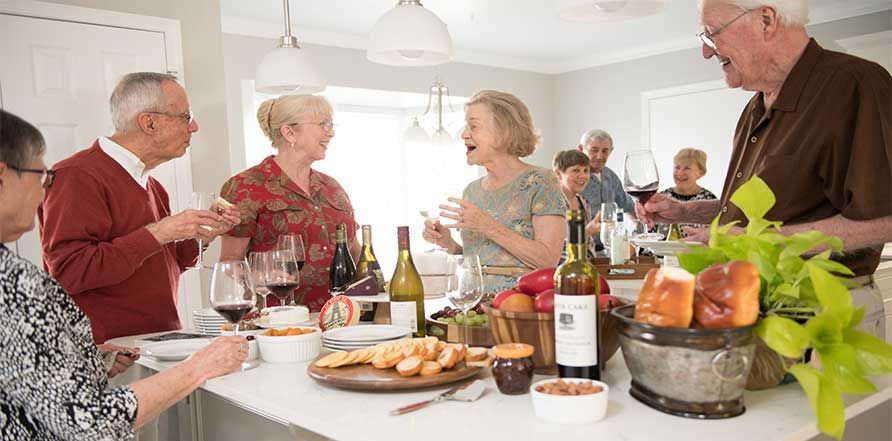 A group of friends enjoying food and drinks together in a kitchen setting.