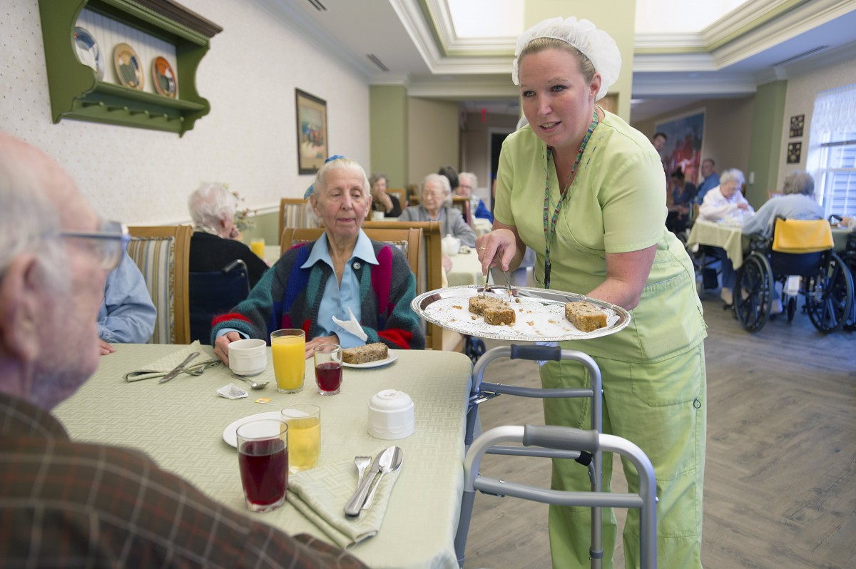 A healthcare worker serving meals to seniors in a nursing home.