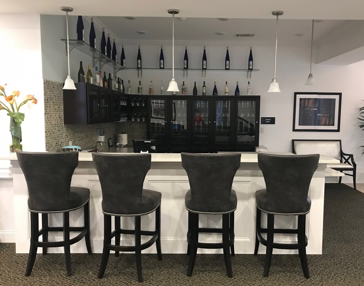 A modern bar setup with high stools and a display of wine bottles.