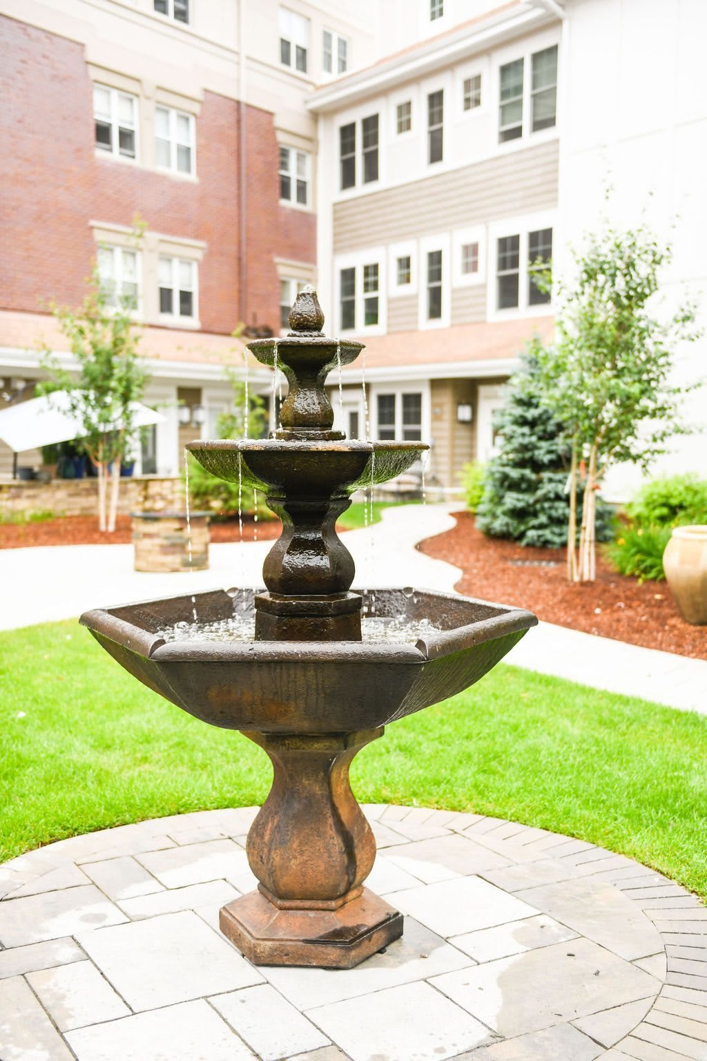 A decorative fountain in a landscaped courtyard surrounded by apartment buildings.