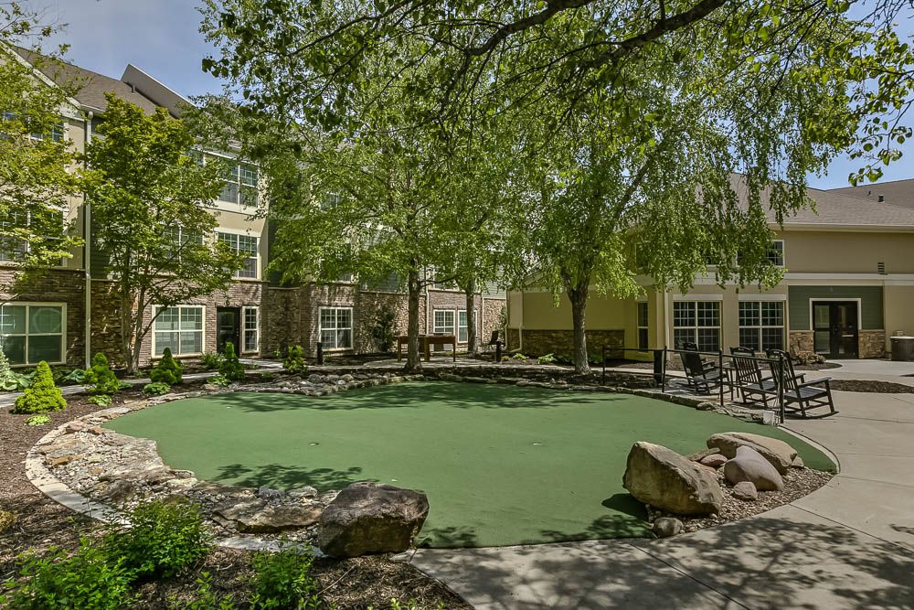 A landscaped outdoor area with trees and a building in the background.