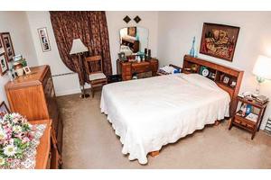 A cozy bedroom with wooden furniture, including a bed, dresser, chair, and lamp.