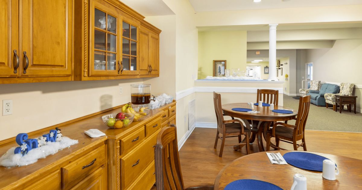 A cozy dining area featuring wooden furniture, a sideboard with a fruit bowl, and a set table.