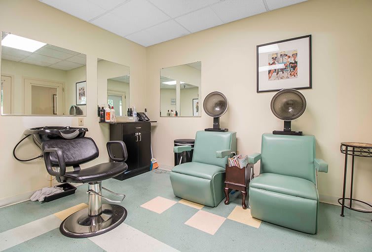 A hair salon with chairs, mirrors, and hair dryers arranged neatly.