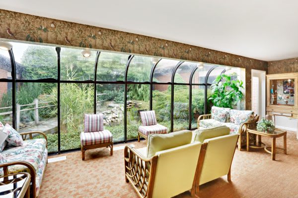 A cozy living room with a panoramic glass wall offering a scenic outdoor view.