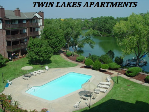 A serene view of Twin Lakes Apartments featuring a sparkling pool and lush surroundings.