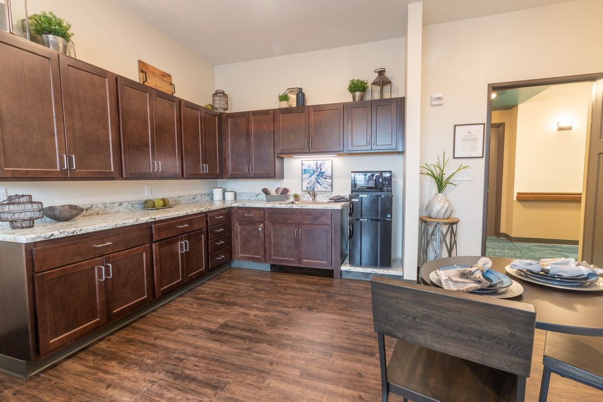 A modern kitchen interior with wooden cabinets and flooring, featuring sleek countertops and contemporary appliances.