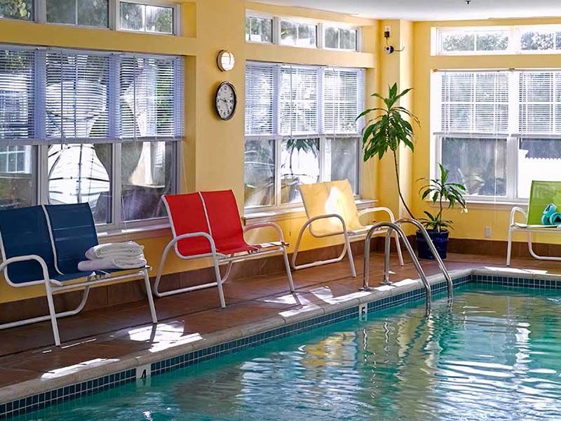 A cozy indoor pool area with colorful chairs and large windows.