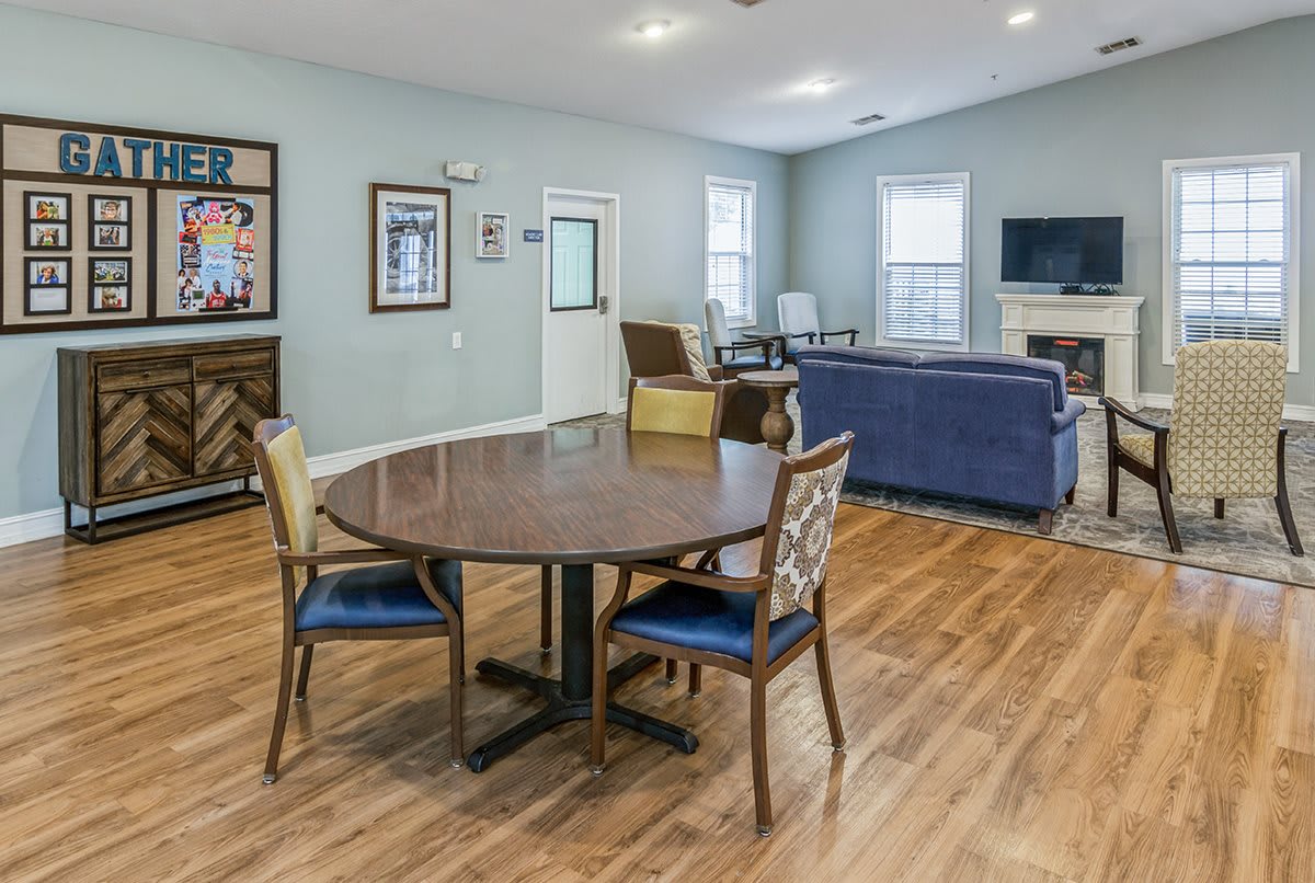 A cozy living room with a round table, chairs, and a blue couch on hardwood flooring.