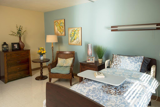 A cozy and well-decorated hospital room featuring calming blue walls and inviting furniture.