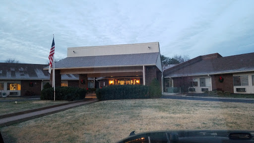 An evening view of a modern building with warm lights illuminating its entrance.