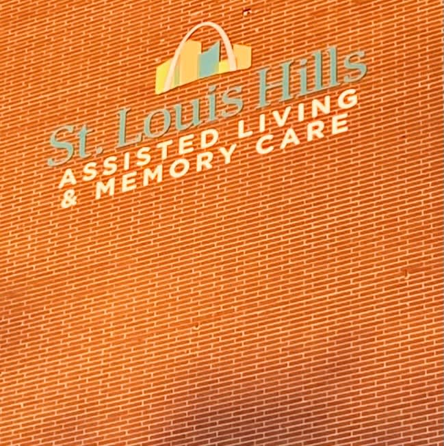 Logo for St. Louis Hills Assisted Living & Memory Care on an orange background.