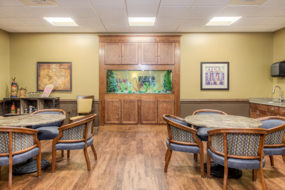 A modern dining area with wooden flooring, featuring an aquarium and artwork on the walls.