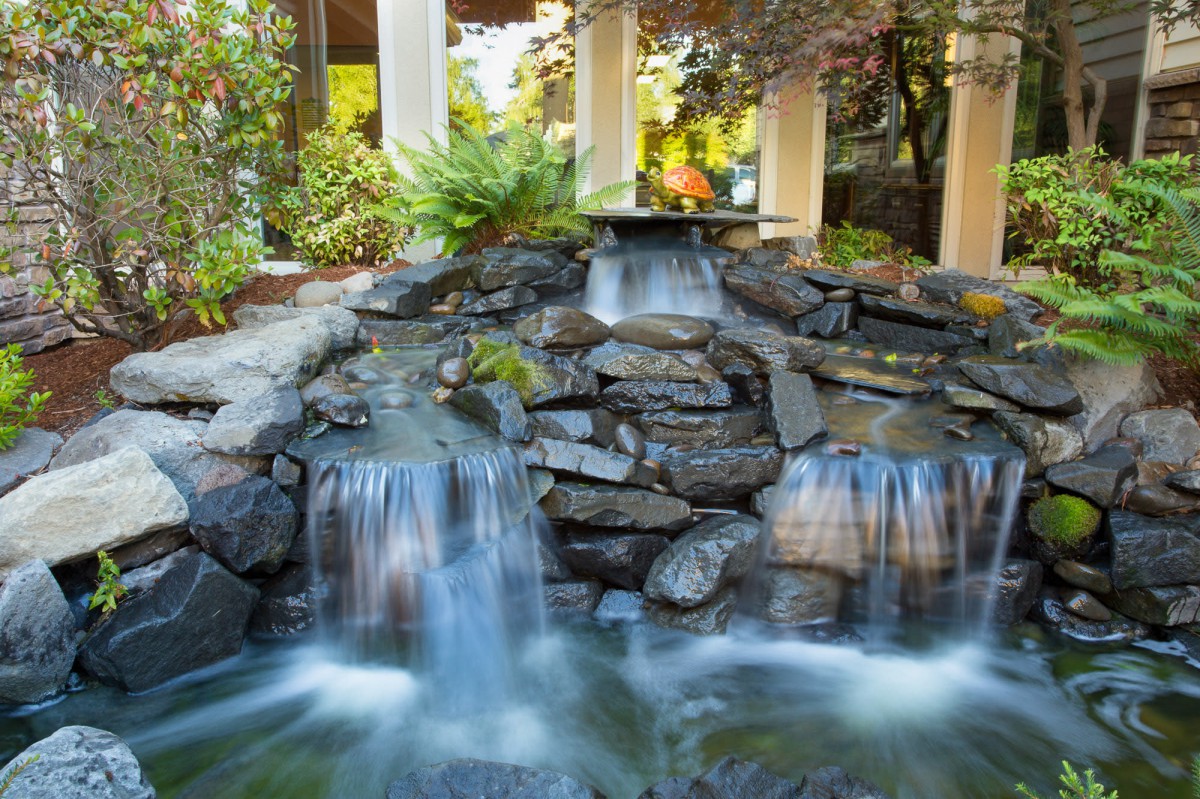 A serene outdoor waterfall cascading over rocks in a garden setting.