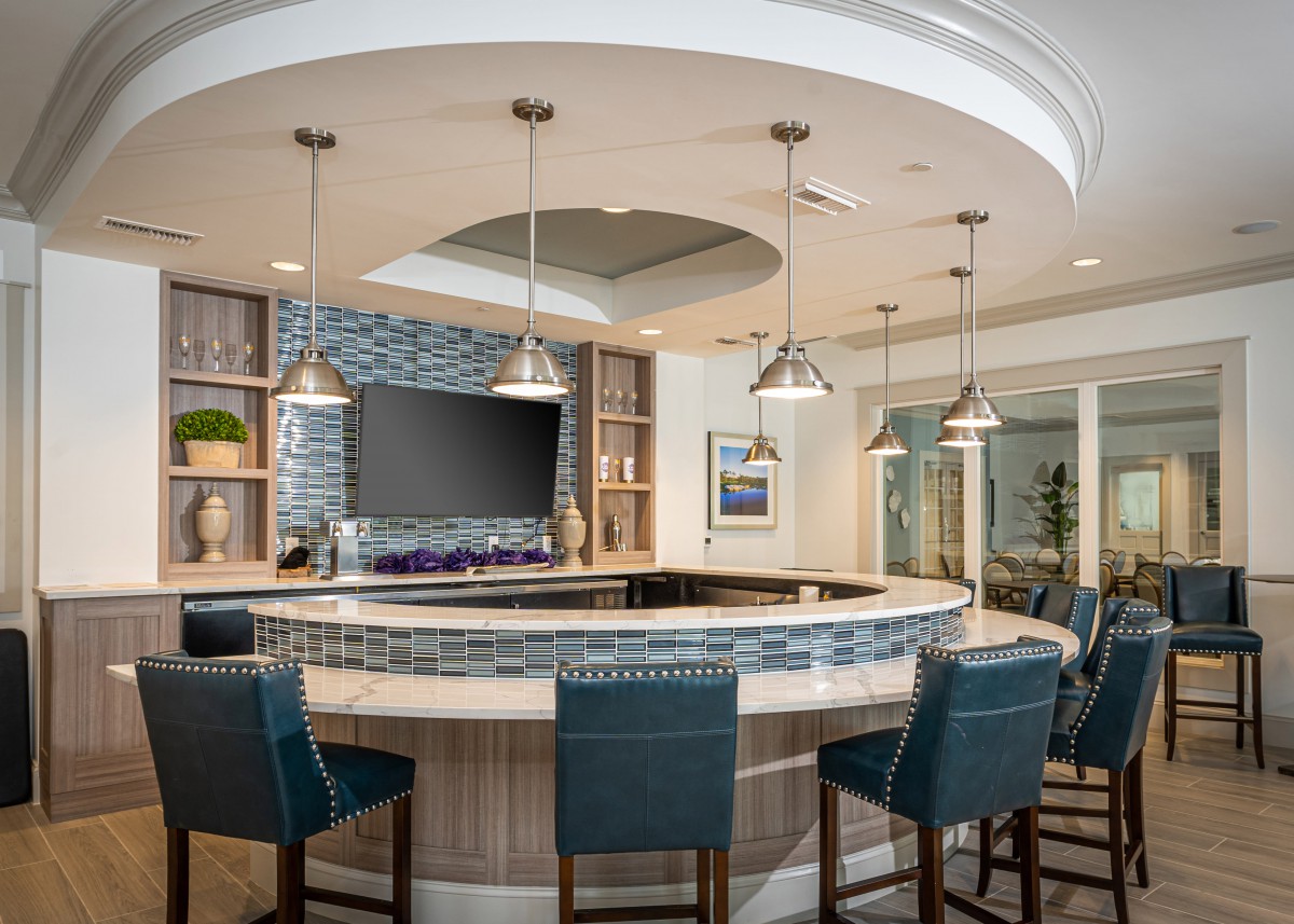 A modern bar area with blue seating, pendant lights, and a television.