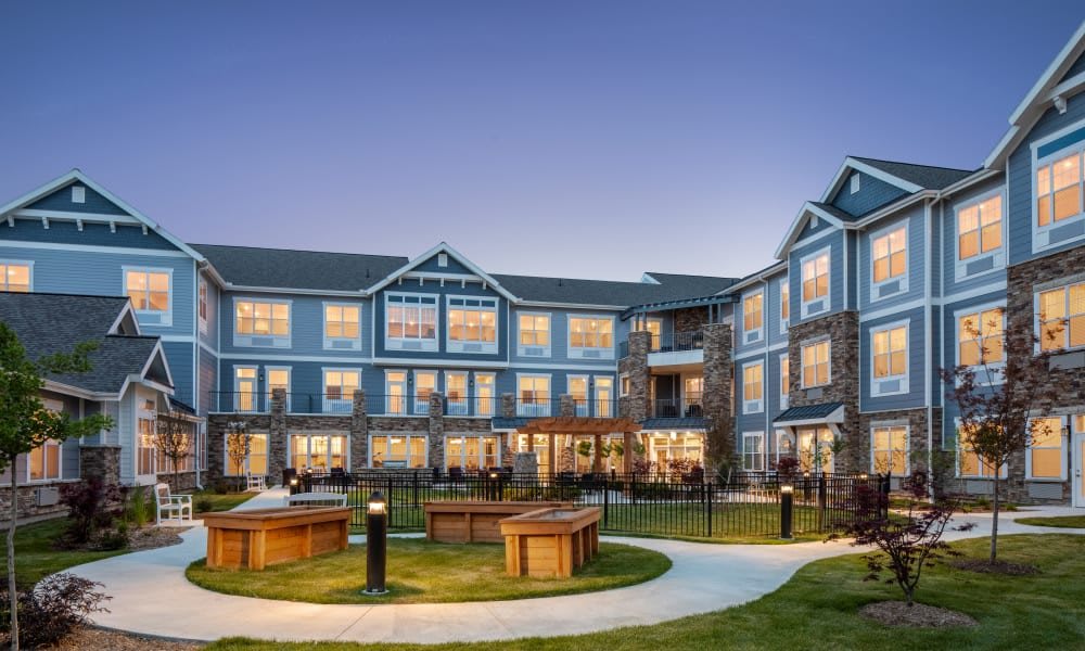 A large residential building with landscaped gardens at twilight.