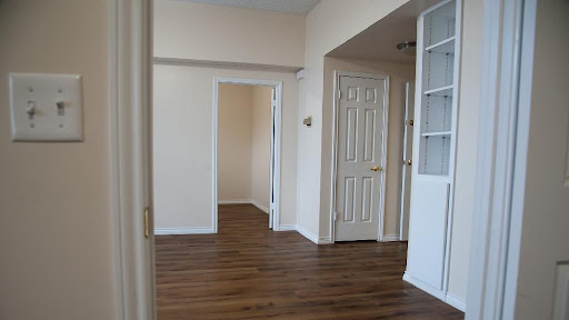 A spacious interior with wooden flooring and several doorways leading to different rooms.
