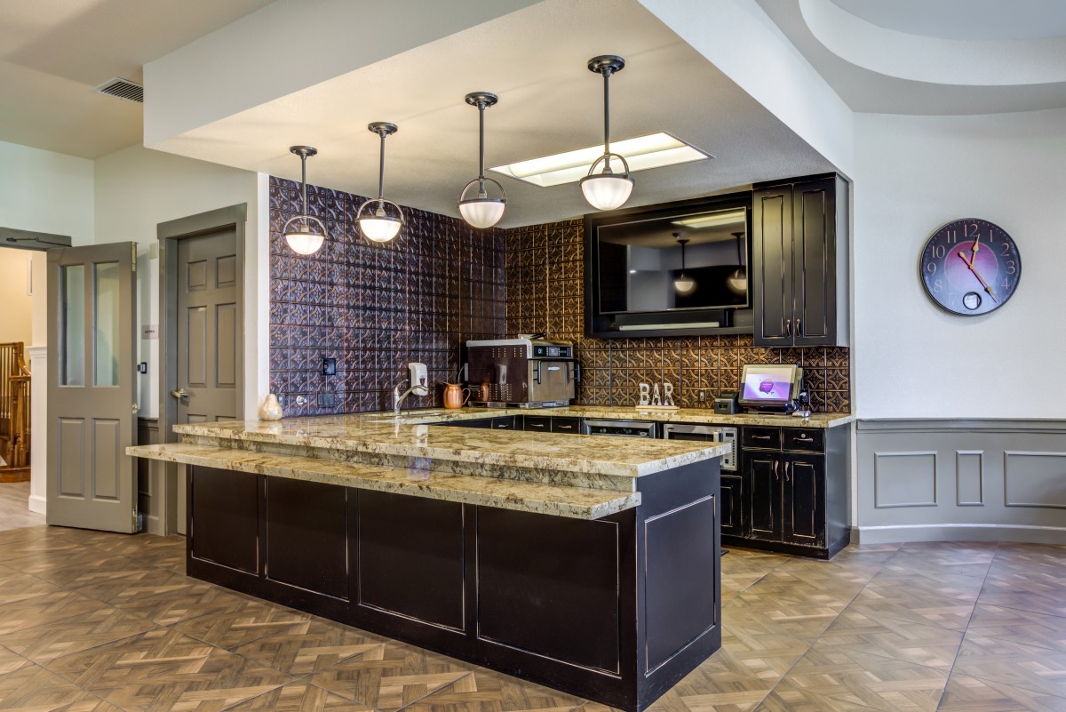 A modern kitchen with dark cabinets, granite countertops, and stylish lighting fixtures.