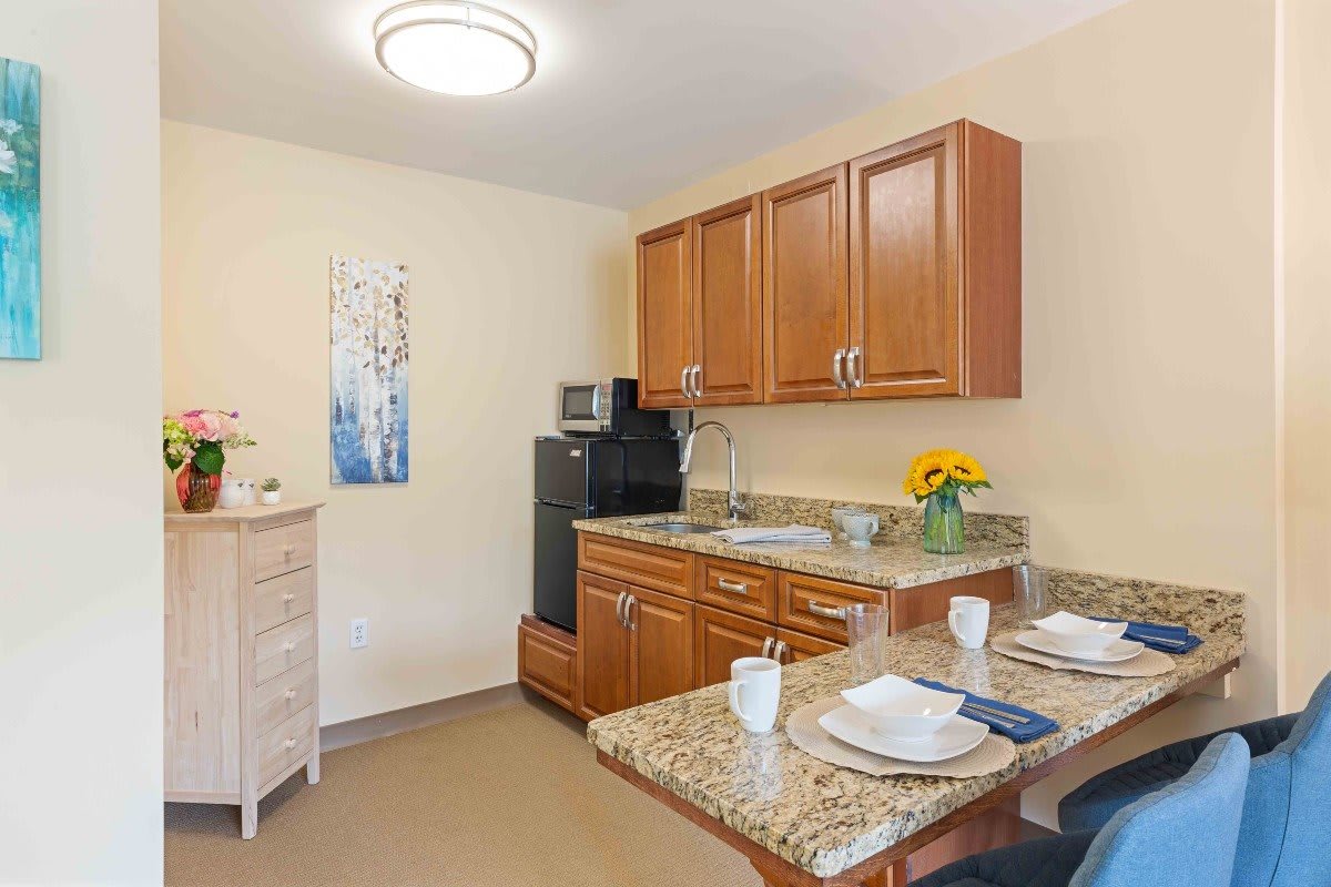 A cozy kitchenette with wooden cabinets, a dining area, and modern appliances.