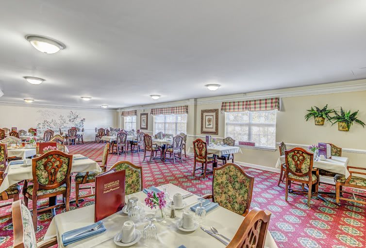 A spacious dining room with elegantly set tables and floral-patterned chairs.