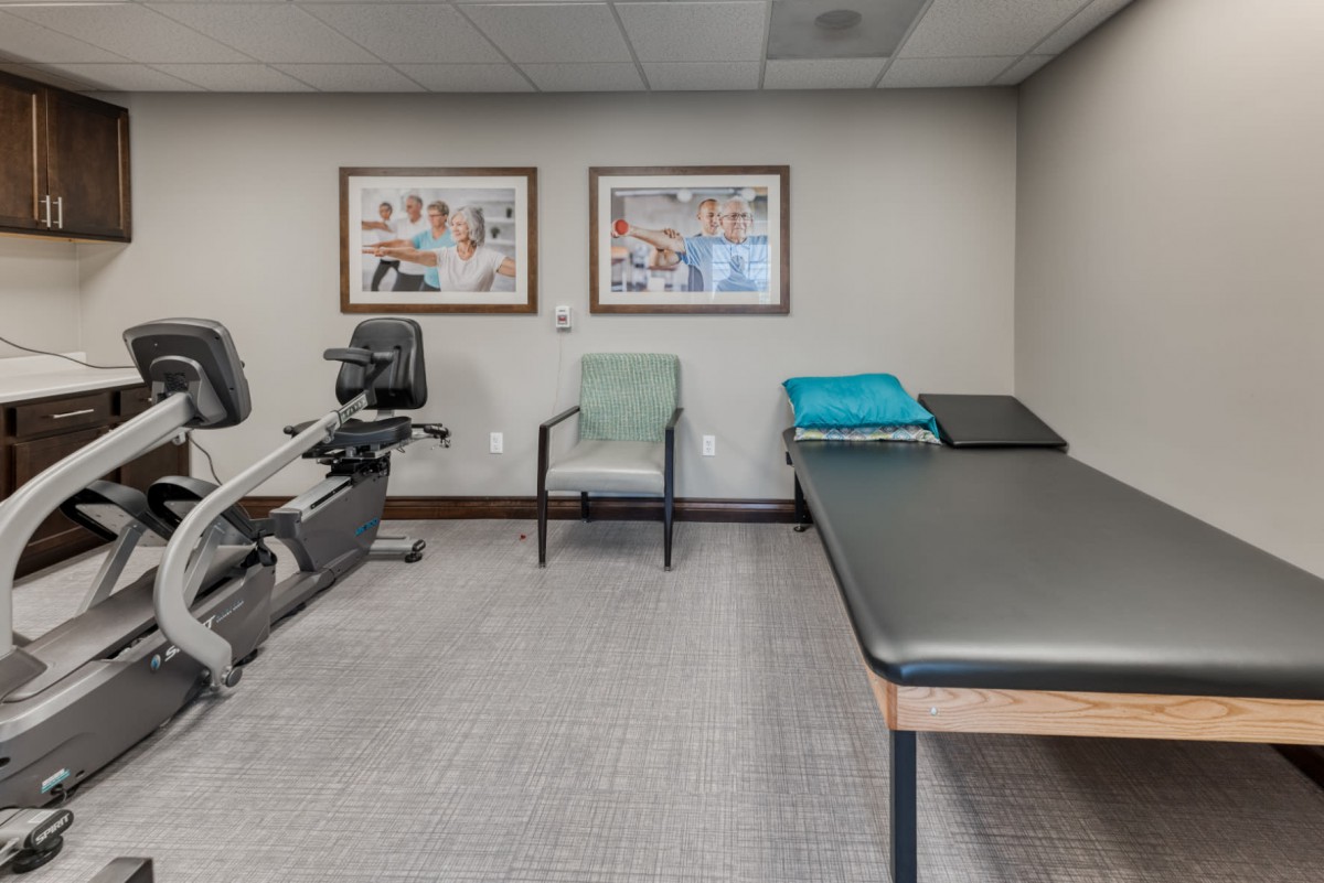 A physical therapy room with exercise equipment and a treatment table.