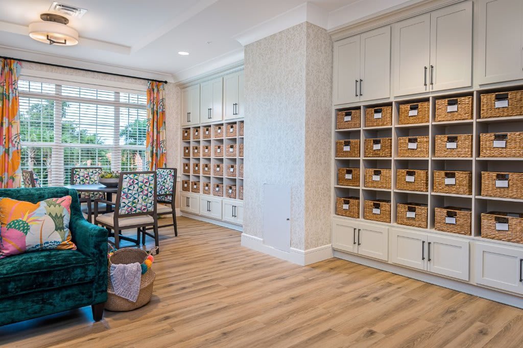 A bright, organized workspace featuring shelves with labeled baskets and a large window.