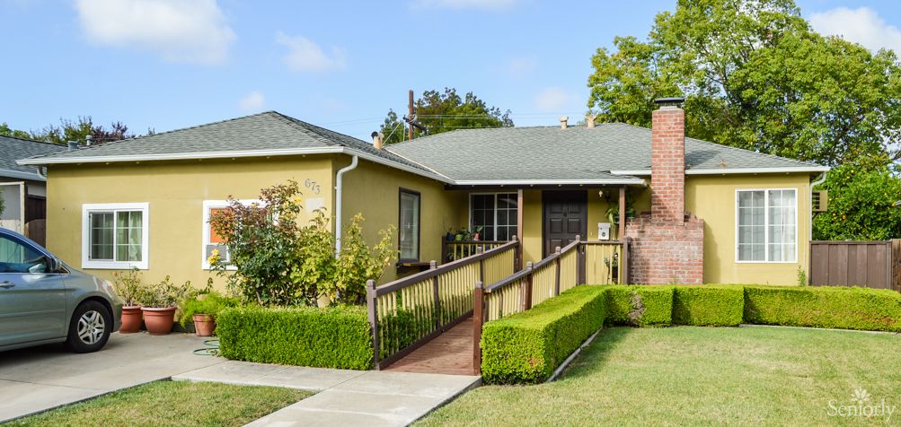 A single-story house with a wheelchair ramp and well-manicured front yard.