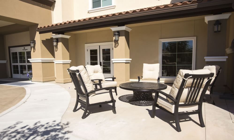A sunny patio with comfortable outdoor furniture set against a beige house.