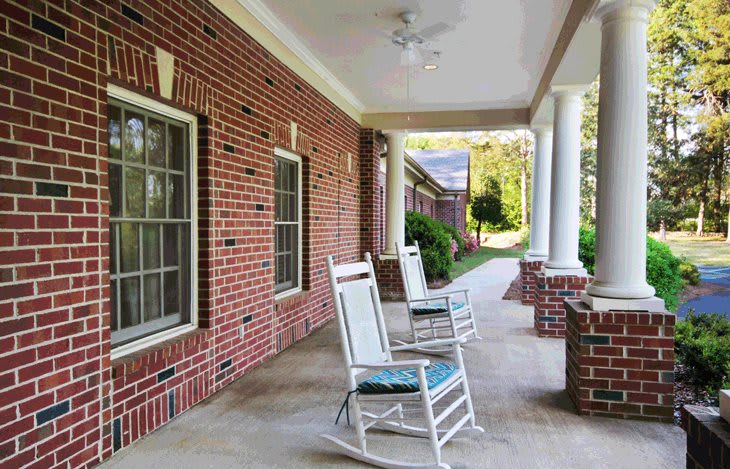 A cozy porch with rocking chairs and brick walls, perfect for relaxation.