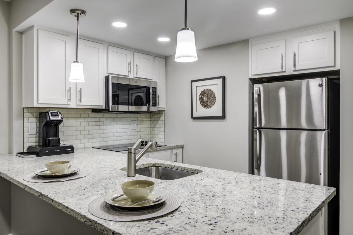 A modern kitchen with stainless steel appliances and pendant lighting.