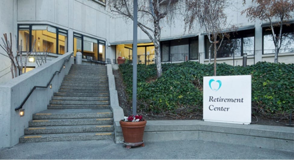 Entrance to a retirement center with stairs leading up and a sign indicating the location.