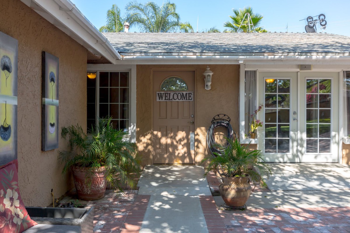 A welcoming house entrance with potted plants and a decorative wooden door.
