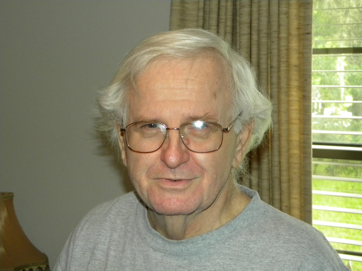 An older man with white hair and glasses indoors.
