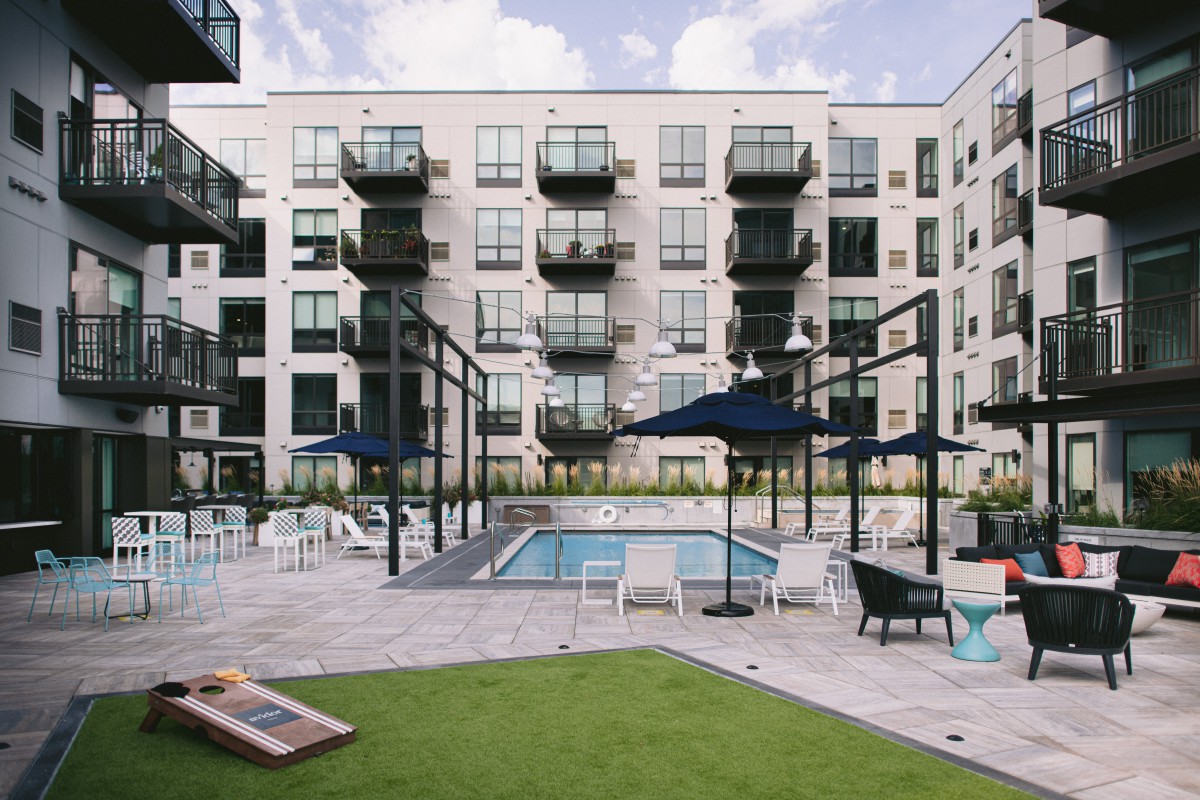 Modern apartment complex with a central pool area and recreational space.