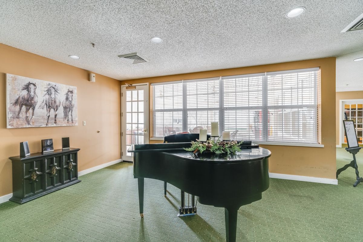 A spacious living room with a grand piano and large windows.