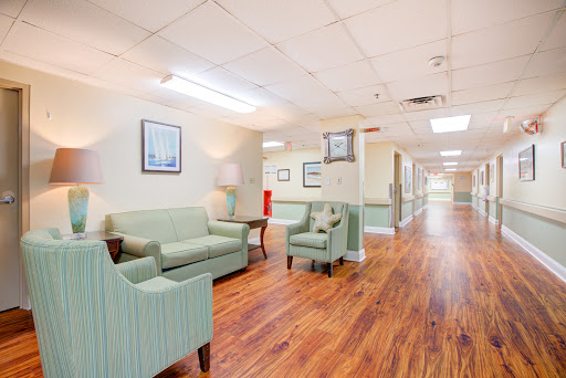 A welcoming waiting area featuring comfortable green furniture and a warm wooden floor.