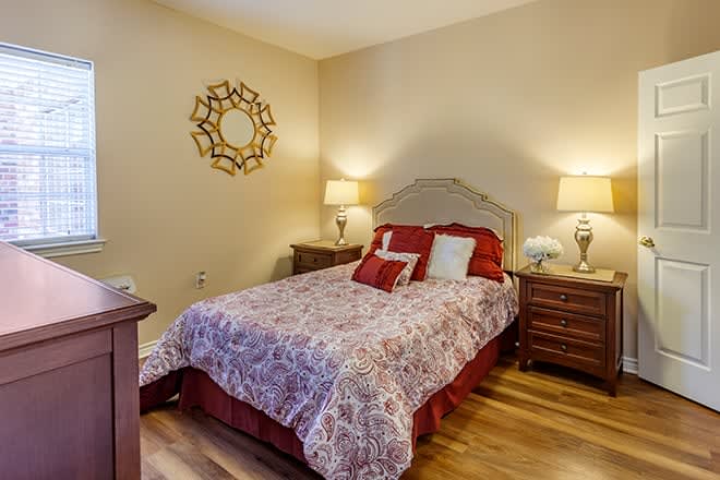 A cozy bedroom with a neatly made bed, decorative pillows, and two bedside tables with lamps.