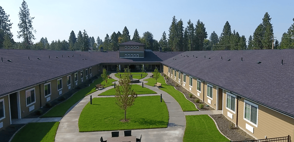 Aerial view of a building with a central courtyard surrounded by green grass and trees.