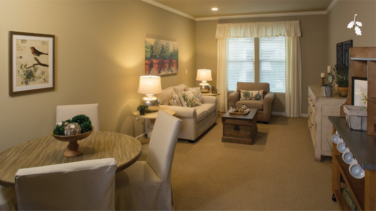 Cozy living room with a sofa, armchair, coffee table, and dining area.