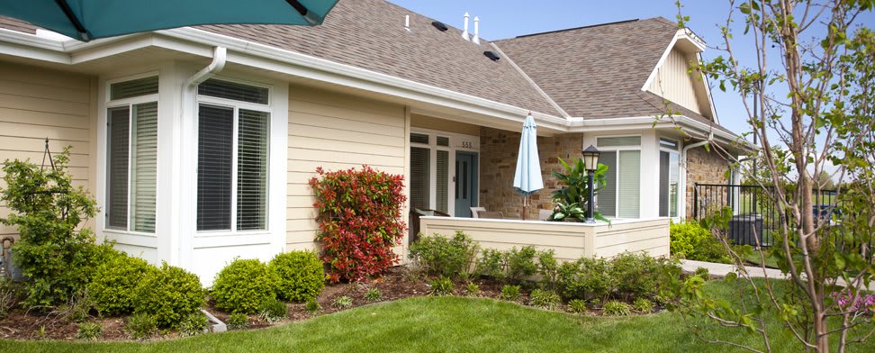 A charming house with a well-maintained garden and a cozy patio area featuring an umbrella.